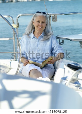 Mature woman on boat with book, smiling, portrait