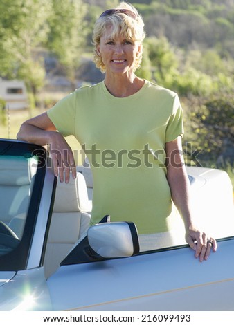 Mature woman by convertible car, smiling, portrait