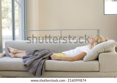 Young woman with book asleep on sofa, profile