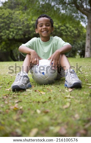 Boy (6-8) with football, smiling, portrait