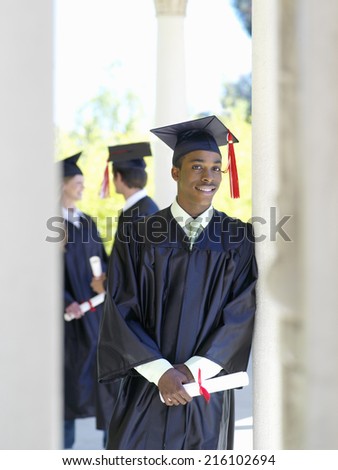 Young man graduating in cap and gown holding diploma