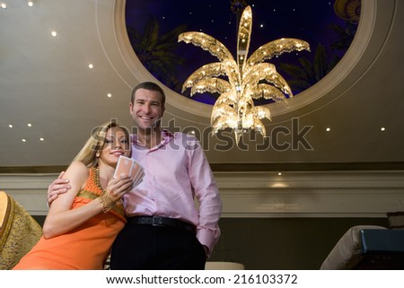 Young couple in casino, woman with hand of cards, smiling, portrait