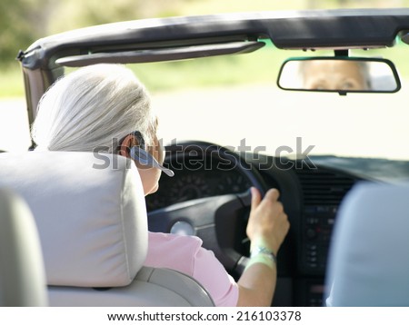 Woman with hands-free device in car, rear view
