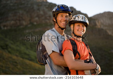Young couple mountain biking in wilderness, man embracing woman, low angle view