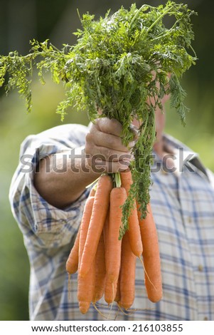 Senior man with carrots obscuring face