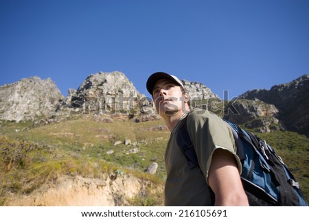 Young man hiking with rucksack, low angle view