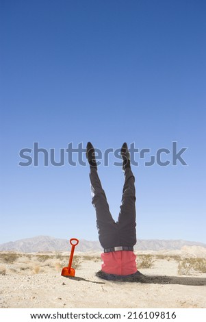 Businessman with head stuck in sand