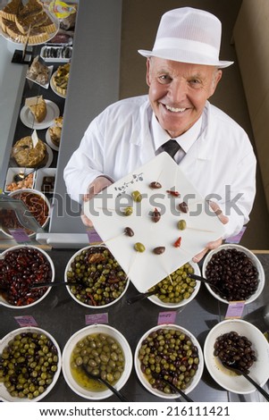 Sales clerk displaying specialty olives