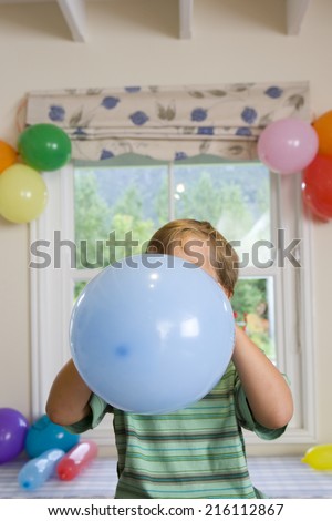 Boy blowing up birthday balloons