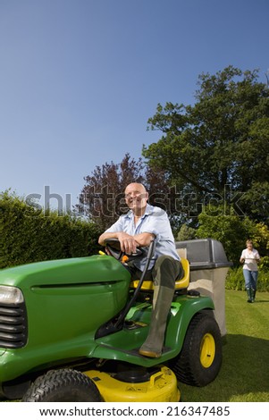 Senior man sitting on riding lawn mower