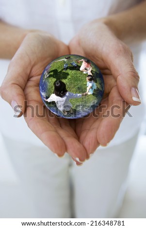 Close up of womanxE4xF3xBBs hands cupping crystal ball globe with children