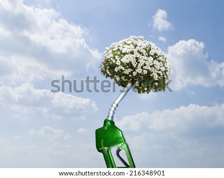 Green gas pump with blooming plant at end of nozzle