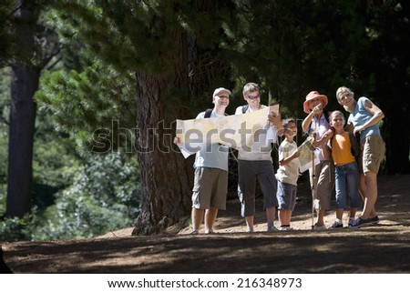 Family standing in woods looking at map