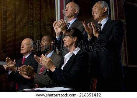 Businesswoman and men clapping in hall, side view