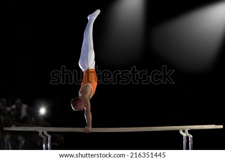 Male gymnast performing handstand on parallel bars, side view
