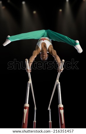 Male gymnast performing on parallel bars, low angle view