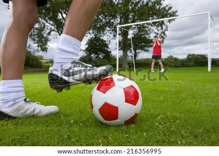 Close up of soccer player aiming ball at frightened goalie