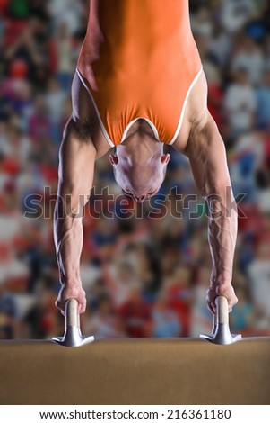 Male gymnast performing handstand on pommel horse