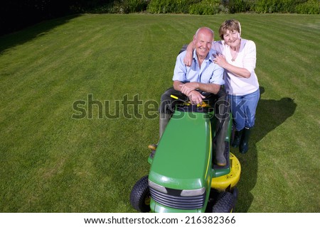 Portrait of woman hugging man on riding lawn mower