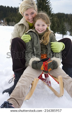 Portrait of mother and daughter on snow sled