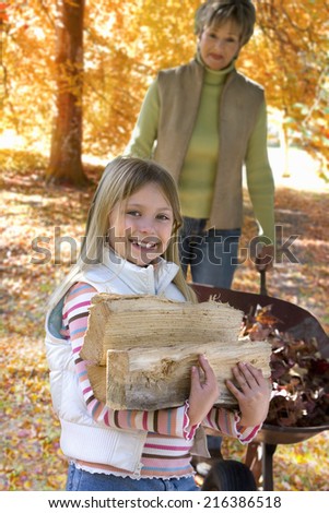 Young girl and grandmother doing yard work in autumn