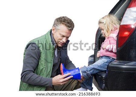 Father placing wellington boot on daughter\'s foot, cut out