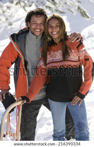 Portrait of mixed race couple with snow sled