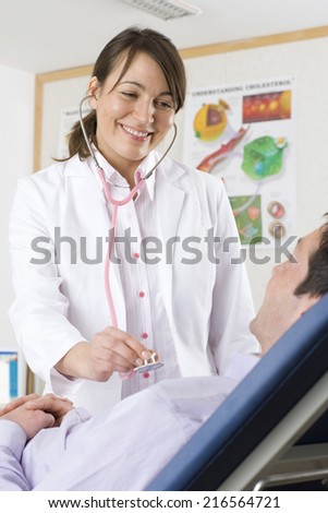 Doctor using stethoscope on patient in examination room