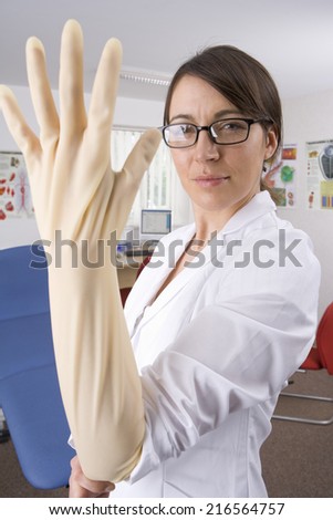 Doctor putting on surgical glove with attitude in examination room
