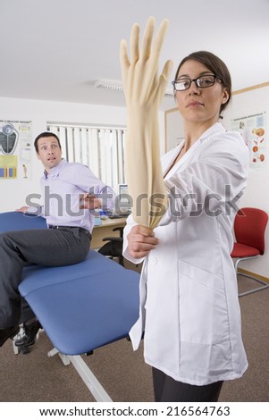 Worried man watching doctor put on surgical glove with attitude in examination room