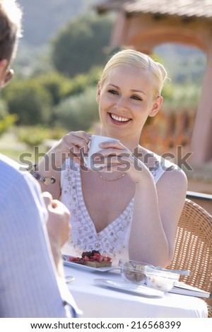 Couple drinking coffee and eating dessert on cafe patio