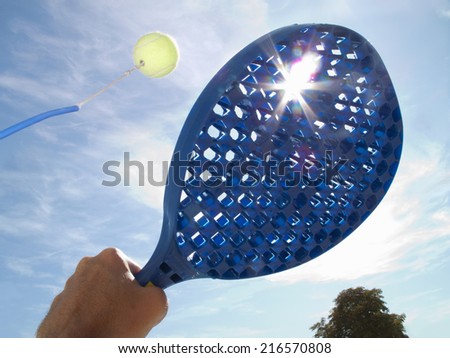 Sun shining behind paddle hitting tennis ball