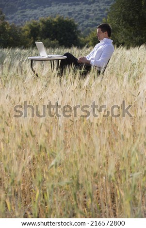 Businessman using laptop at table in rural field