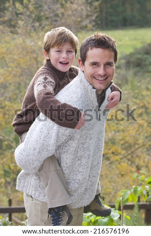 Smiling father giving son piggyback ride outdoors