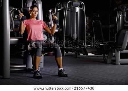Woman weight lifting with exercise equipment in health club