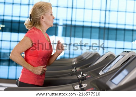 Senior woman running on treadmill in health club
