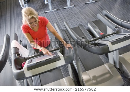 Senior woman programming treadmill in health club