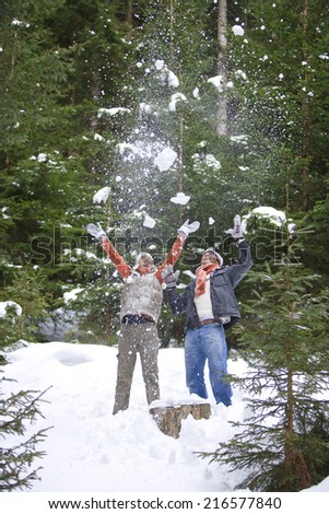 Playful couple throwing snow in woods