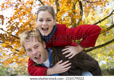 Husband giving woman piggyback ride outdoors