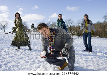 Friends having snowball fight in snowy field