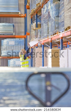Female warehouse worker lifting box from shelf