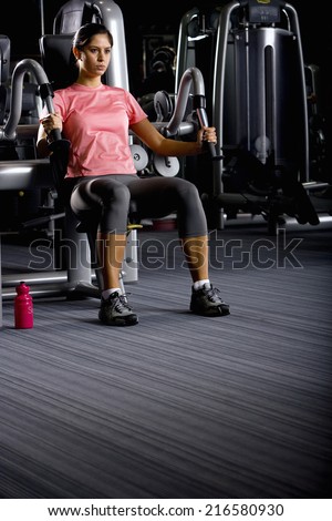 Woman weight lifting with exercise equipment in health club