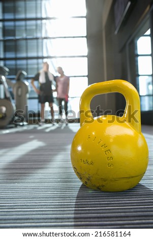 Yellow medicine ball on floor in health club with couple in background