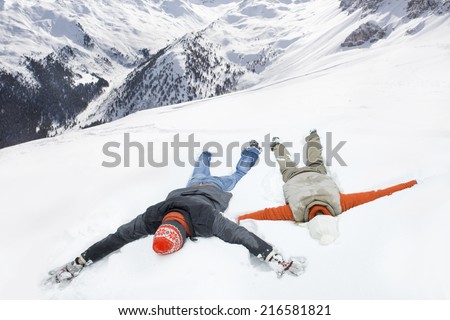 Couple making snow angels on mountain