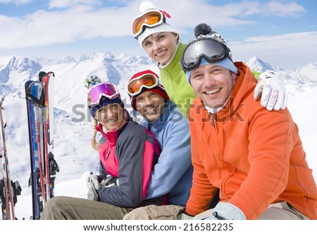 Smiling friends sitting with skis in snow