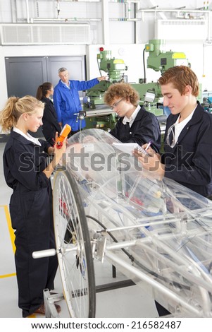 Students constructing electric vehicle prototype in vocational school