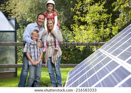 Happy family standing near large solar panels