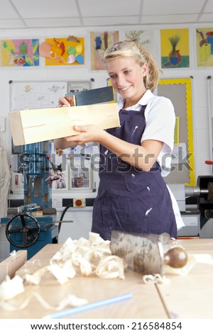 Smiling student measuring planed wood in vocational school