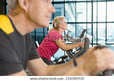 Man and woman riding exercise bikes in health club