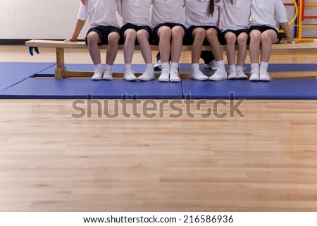 School children sitting on bench in school gymnasium